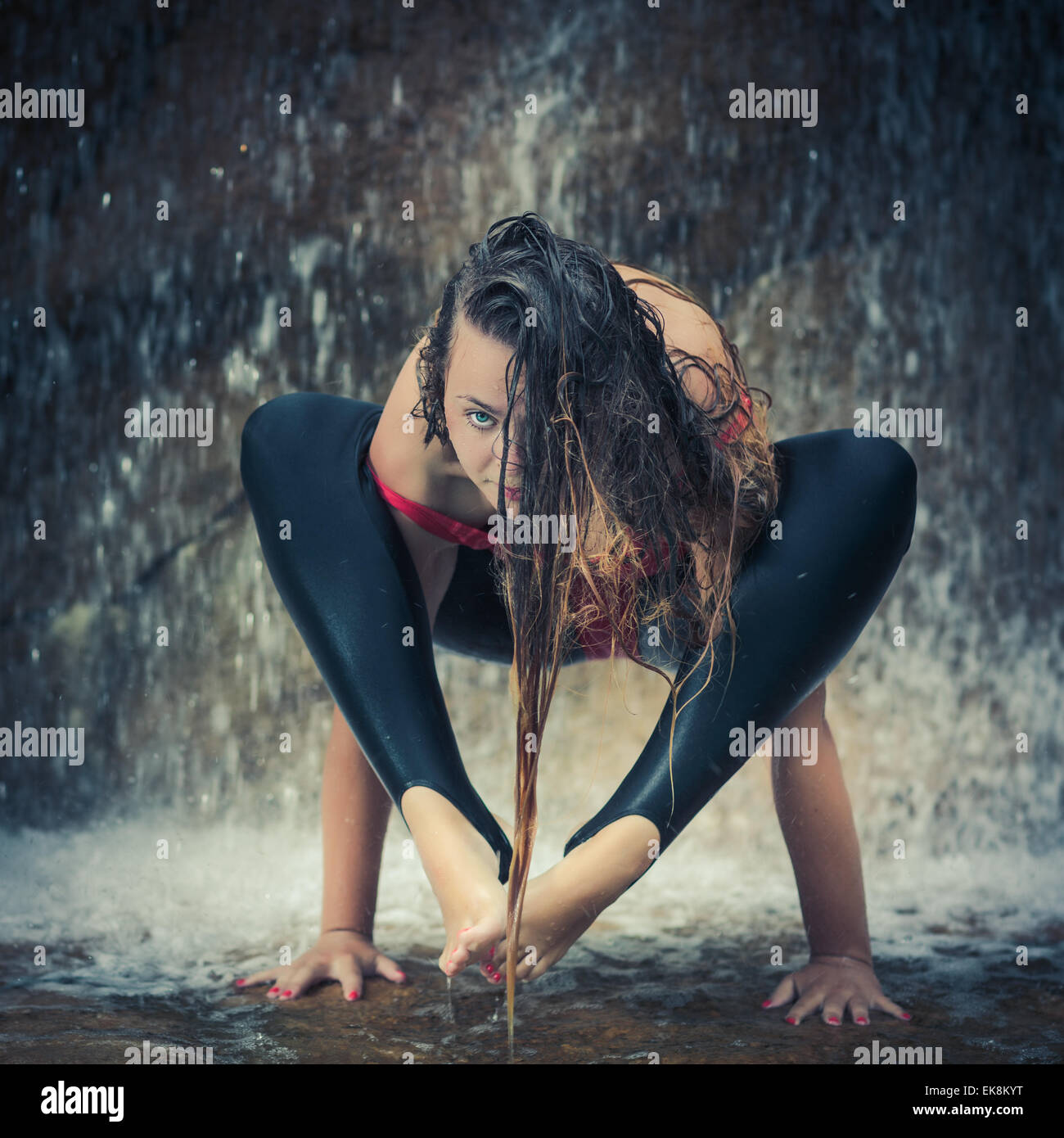 Frau Yoga zu praktizieren in der Nähe von Wasserfall. Schulter drücken Haltung. Bhujapidasana Stockfoto
