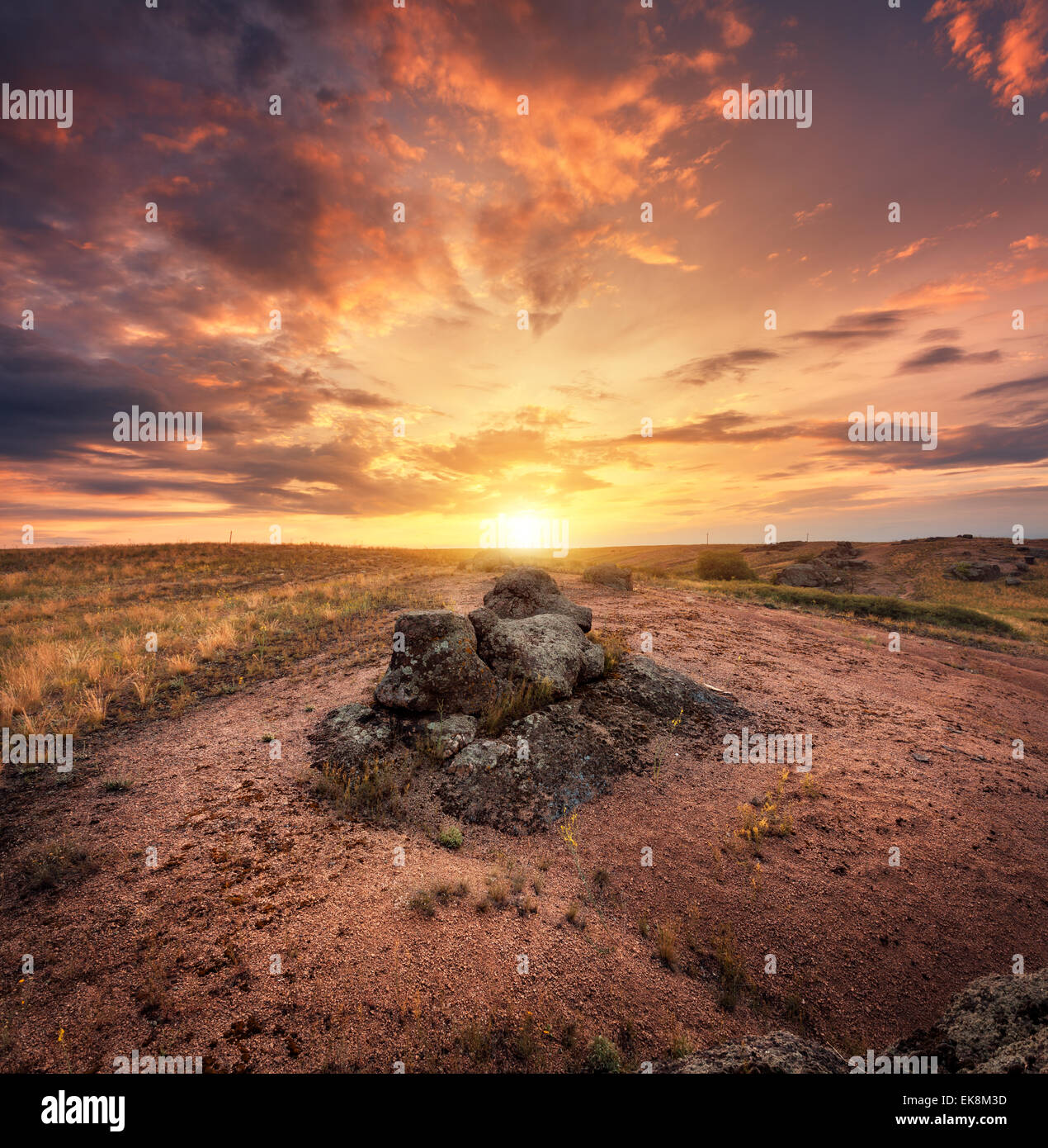 Schönen Sommer Sonnenuntergang mit roter Himmel, orange Wolken, Felsen und gelben Grases in der Ukraine Stockfoto