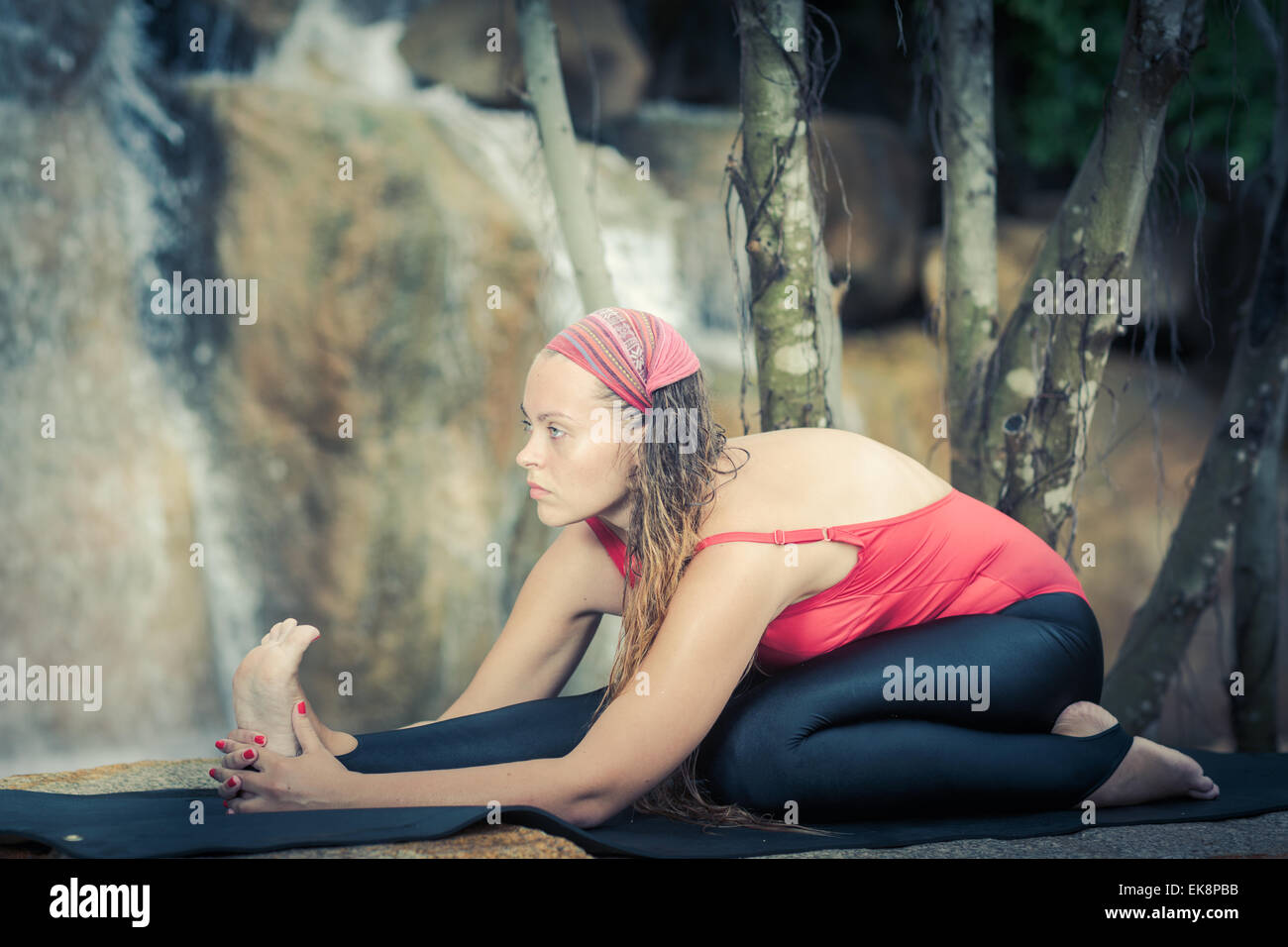 Frau Yoga zu praktizieren in der Nähe von Wasserfall. Halbe Strecke Held. Ardha Virasana Stockfoto