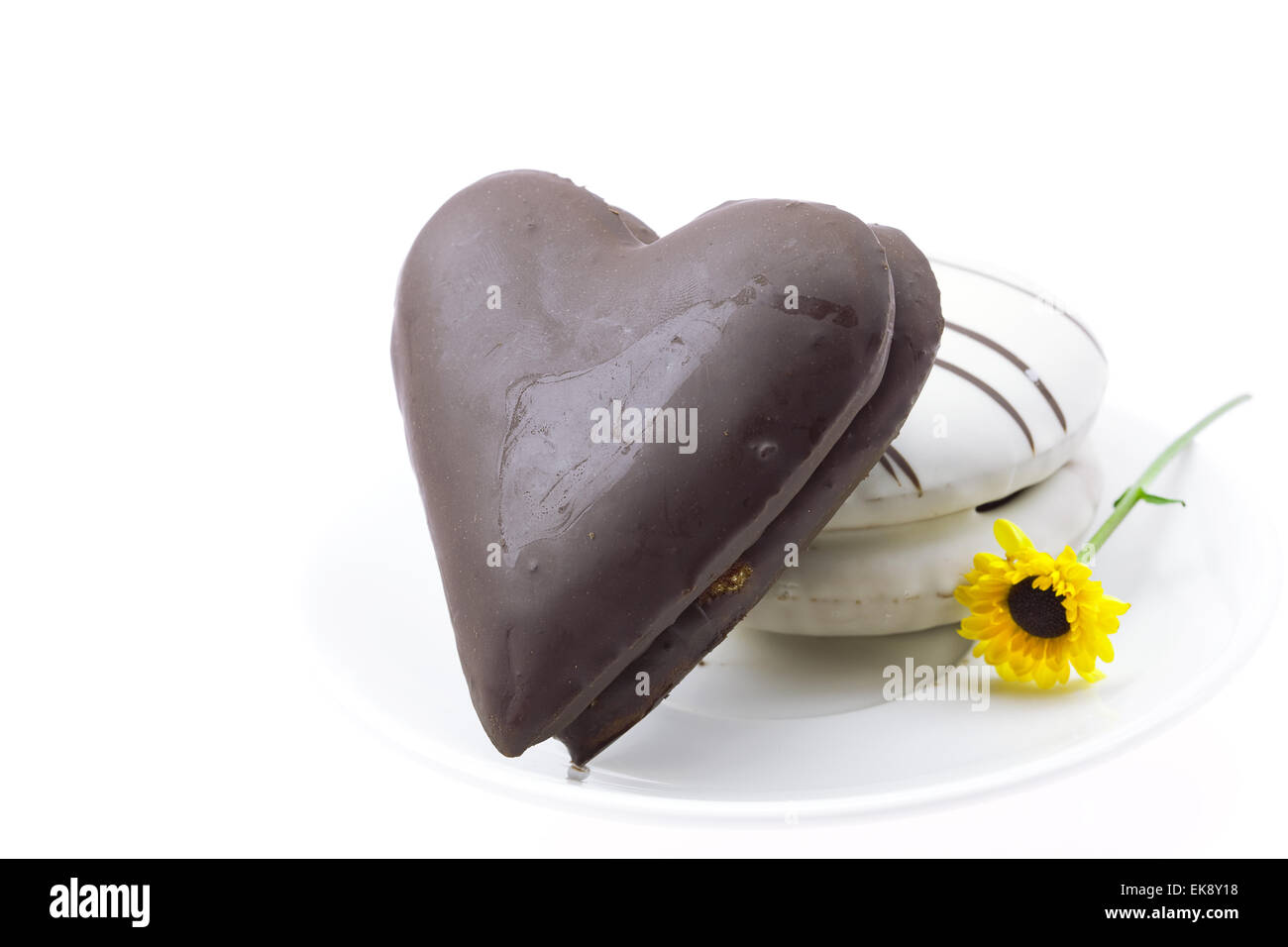 Kuchen in der Form Herz und Blume auf einem Teller isoliert auf weiss Stockfoto