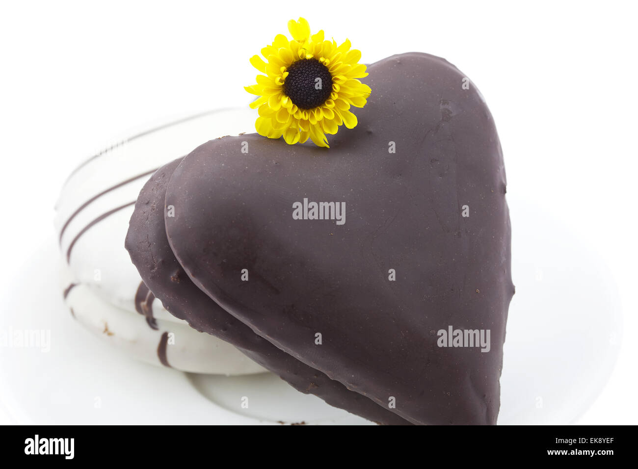 Kuchen in der Form des Herzens und eine Blume isoliert auf weiss Stockfoto