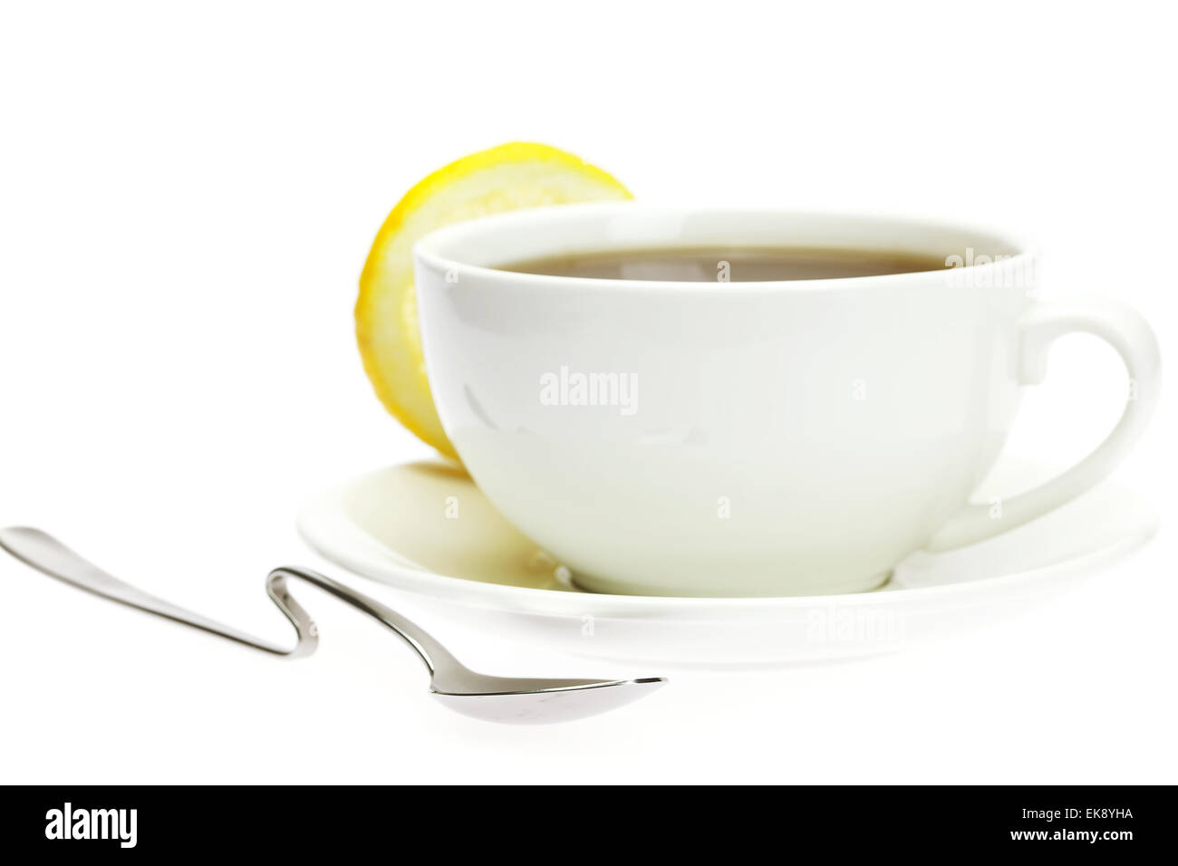 weiße Tasse, ein Löffel und eine Zitrone, isoliert auf weiss Stockfoto