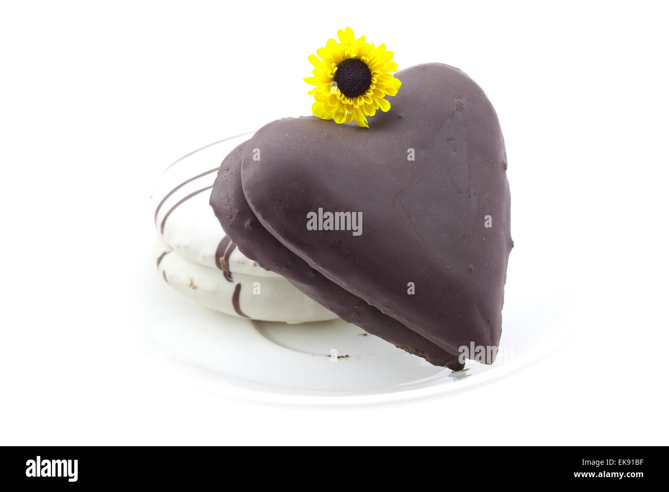 Kuchen in der Form des Herzens und eine Blume isoliert auf weiss Stockfoto
