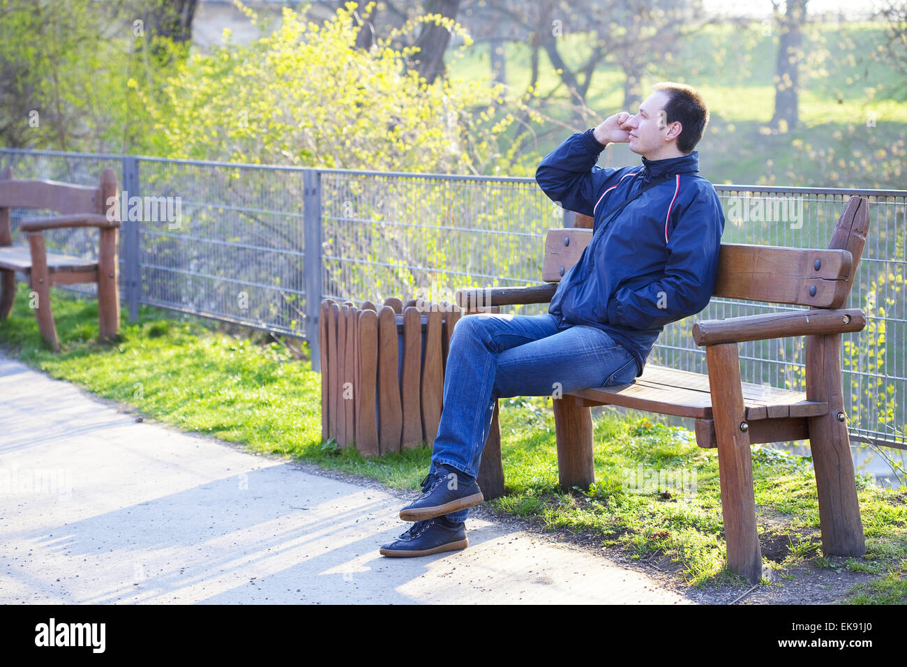 Mann sitzt auf einer Parkbank reden über Handy Stockfoto