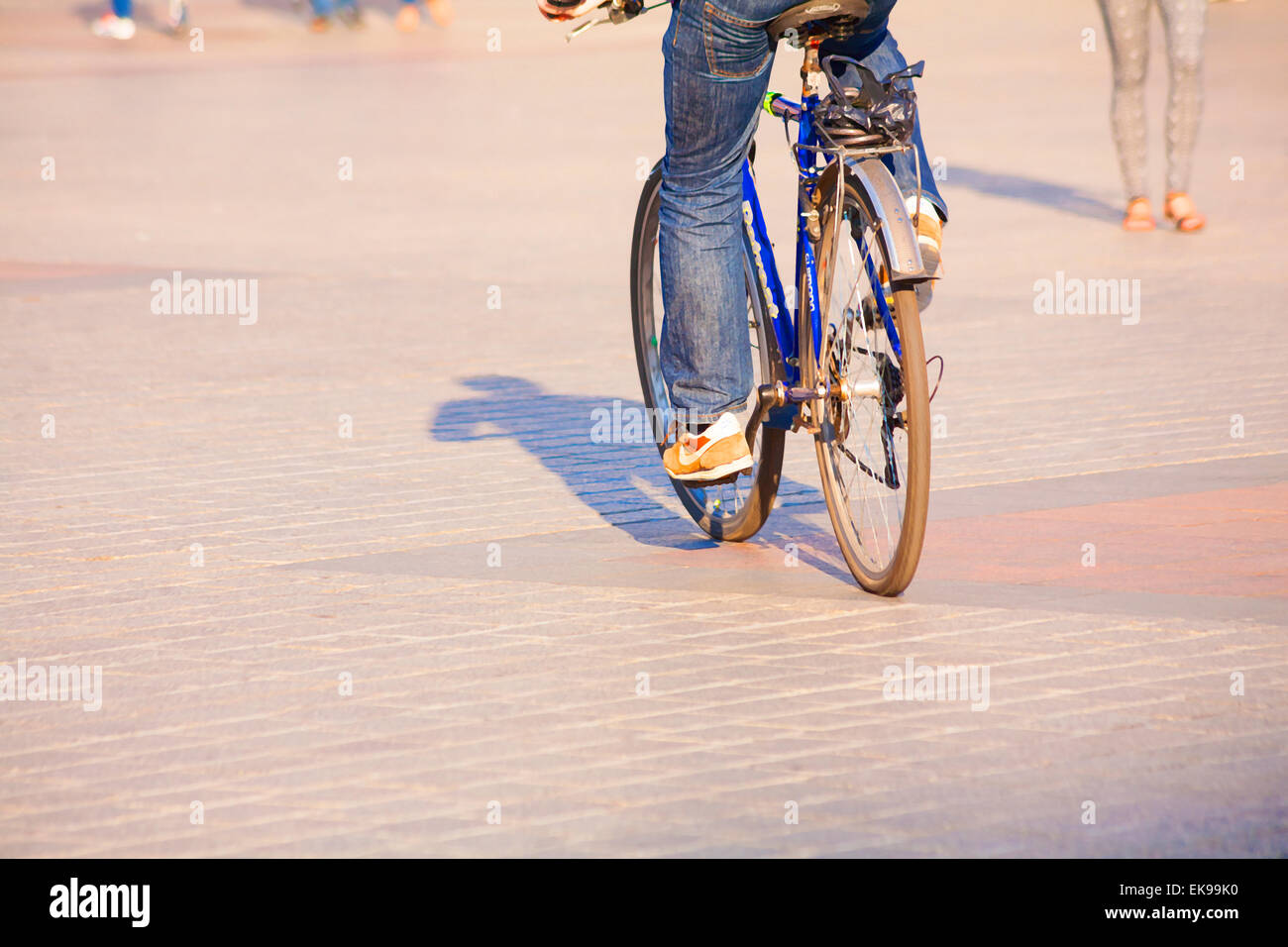 Malerische Wirkung der Radfahrer Schatten Radfahren mit Füßen von Fußgängern auf dem Marktplatz, Krakau, Polen im September Stockfoto