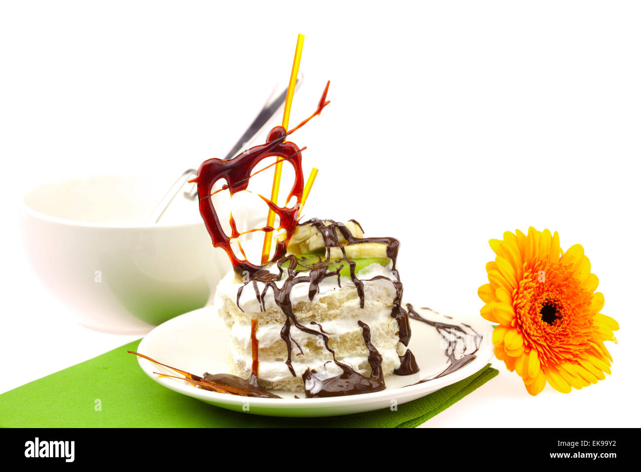 Kuchen mit Creme Caramel Herz und Gerbera auf einem grünen Tuch liegend Stockfoto