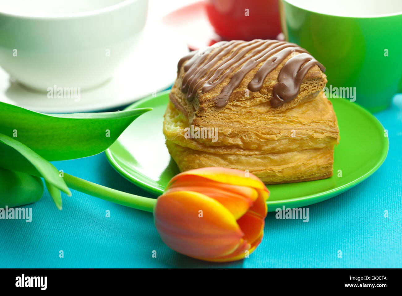 Kuchen mit Schokolade auf dem Teller, Tulpe und eine Tasse auf den Stoff Stockfoto
