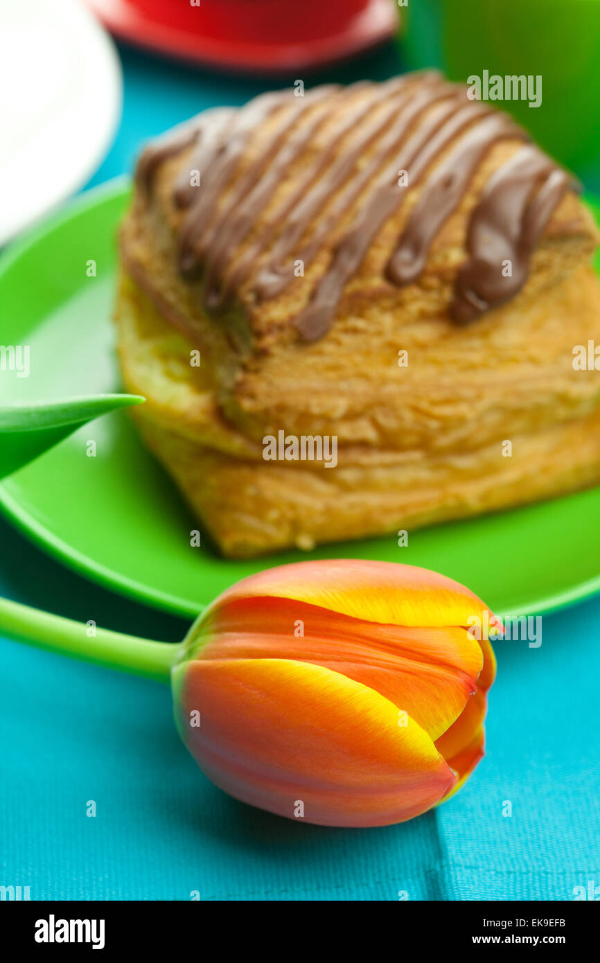 Kuchen mit Schokolade auf dem Teller, Tulpe und eine Tasse auf den Stoff Stockfoto