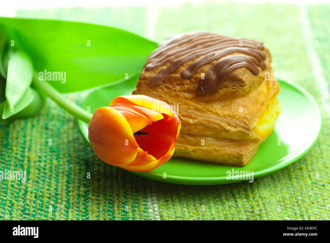 Kuchen mit Schokolade und Tulpen auf einem Teller auf den Stoff Stockfoto