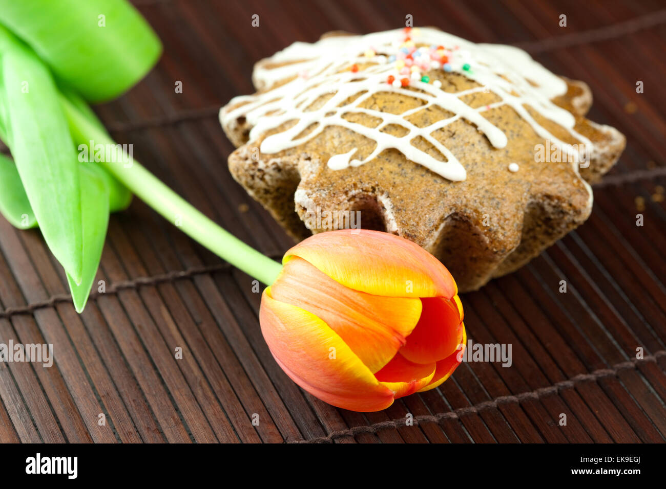 Kuchen mit Zuckerguss und eine Tulpe, liegend auf einer Bambusmatte Stockfoto