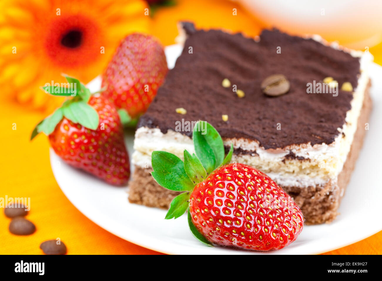 Gerbera, Kuchen und Erdbeeren auf die orangen Stoff liegen Stockfoto