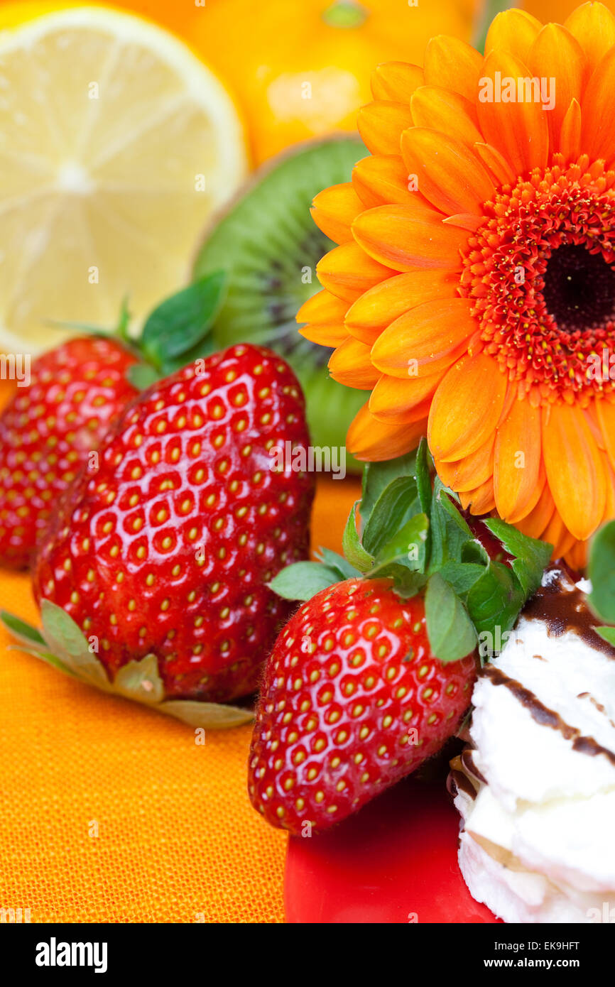 Zitrone, Gerbera, Kuchen und Erdbeeren auf die orangen Stoff liegen Stockfoto