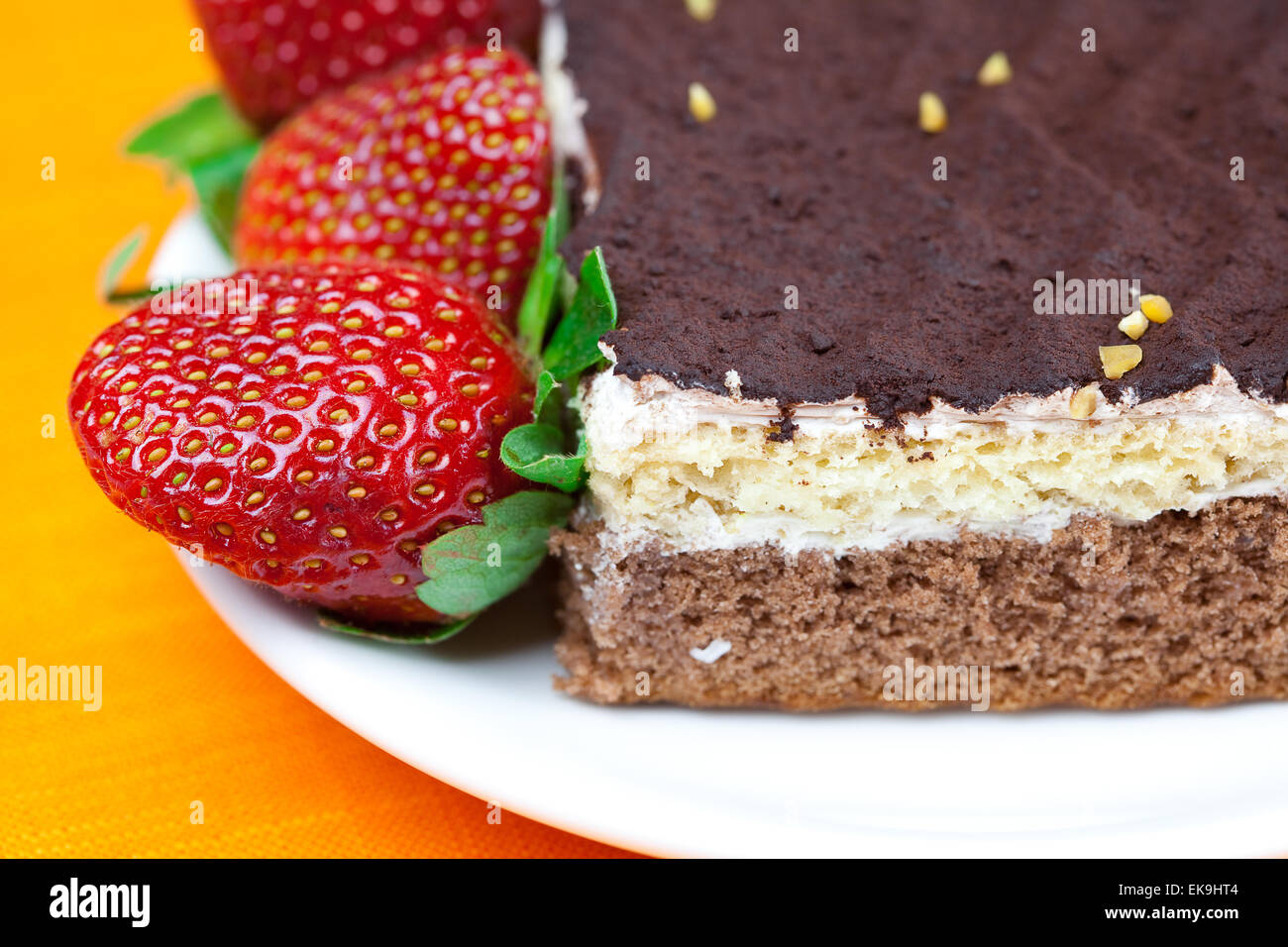 Kuchen auf einen Teller und Erdbeeren auf die orangen Stoff liegen Stockfoto