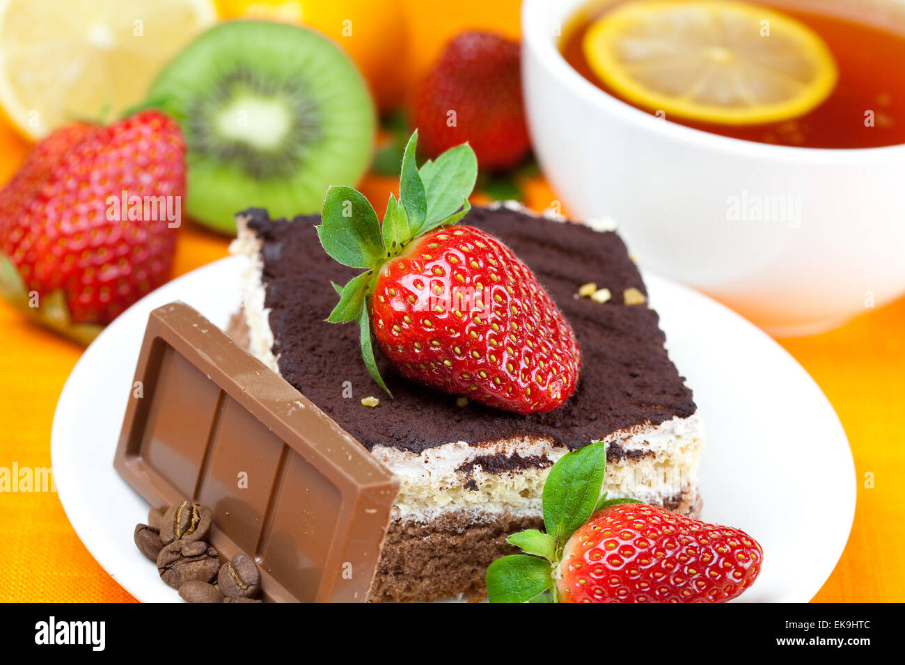 Tee mit Zitrone, Schokolade, Kiwi, Kuchen und Erdbeeren auf der Ora liegend Stockfoto