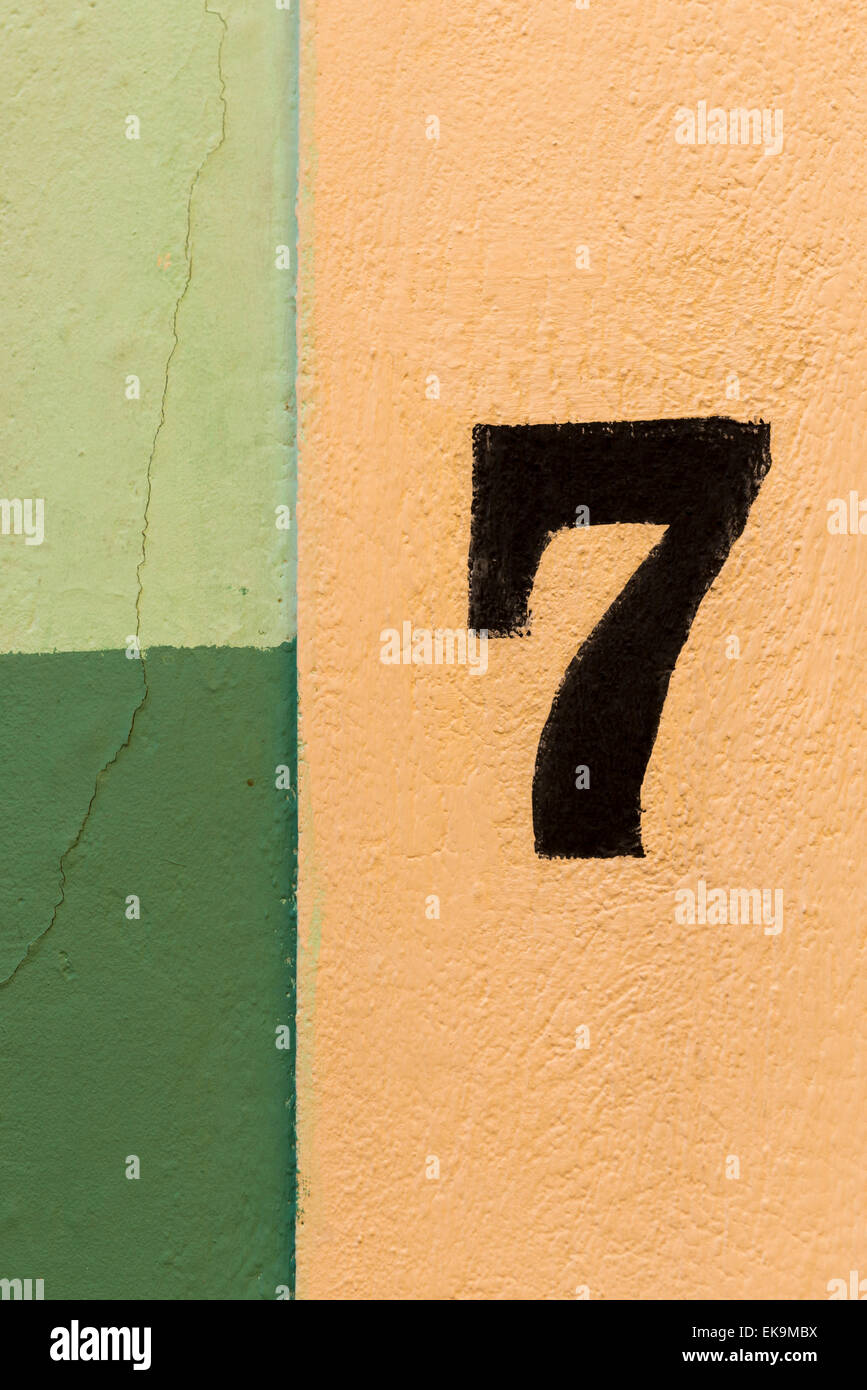 Die Zahl sieben auf eine bunte Wand von gelben und grünen Flecken gemalt Stockfoto