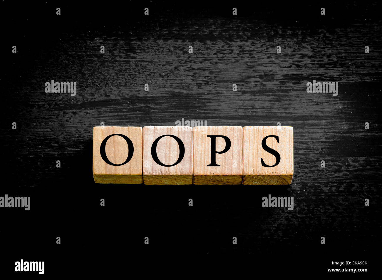 Das Wort OOPS. Hölzerne kleine Würfel mit Buchstaben auf schwarzem Hintergrund mit Kopie Speicherplatz isoliert. Konzept-Bild. Stockfoto