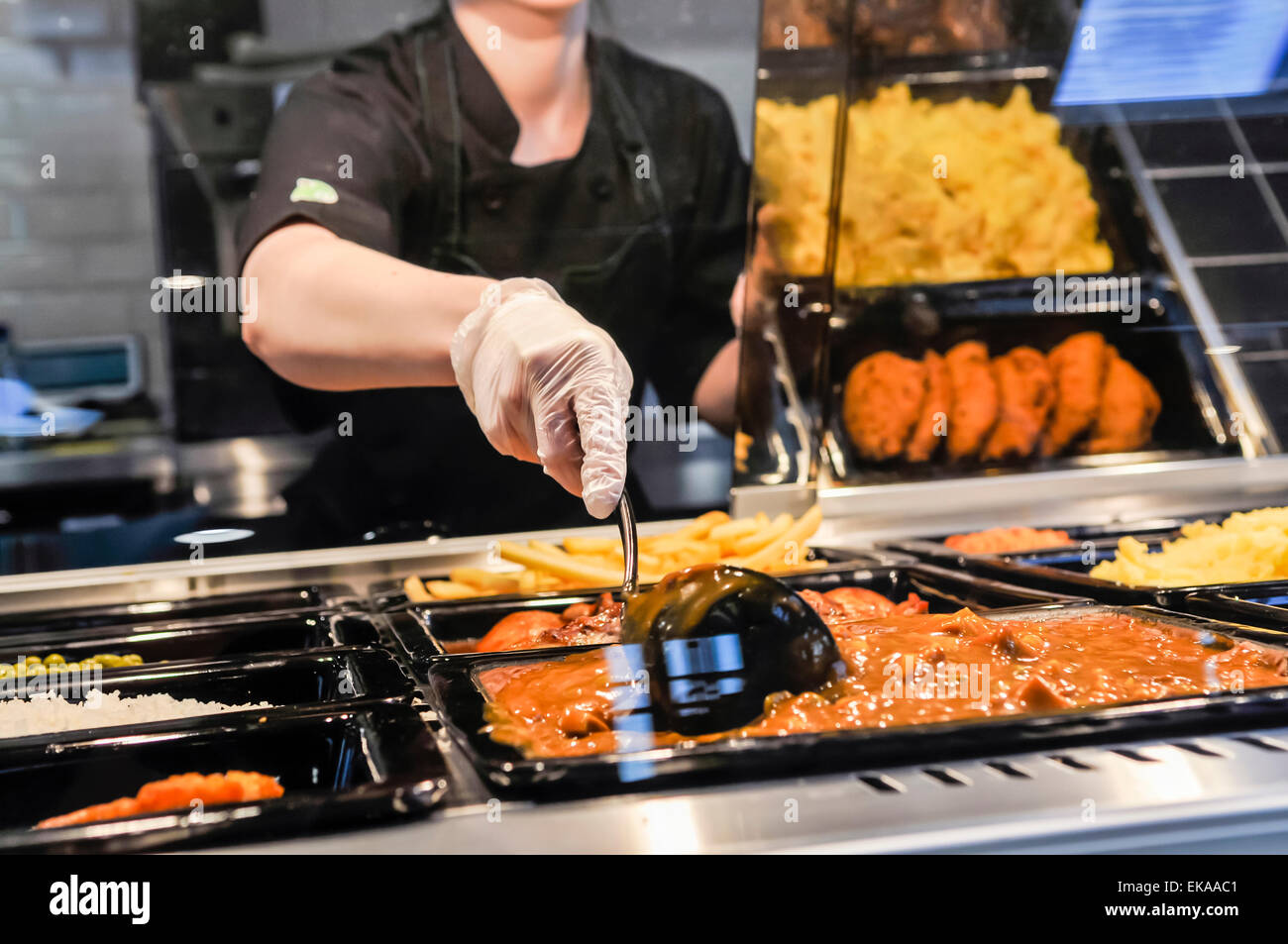 Eine Frau regt sich eine Schüssel mit Chili Con Carne an der Bedientheke in einer Autobahn-Tankstelle-café Stockfoto