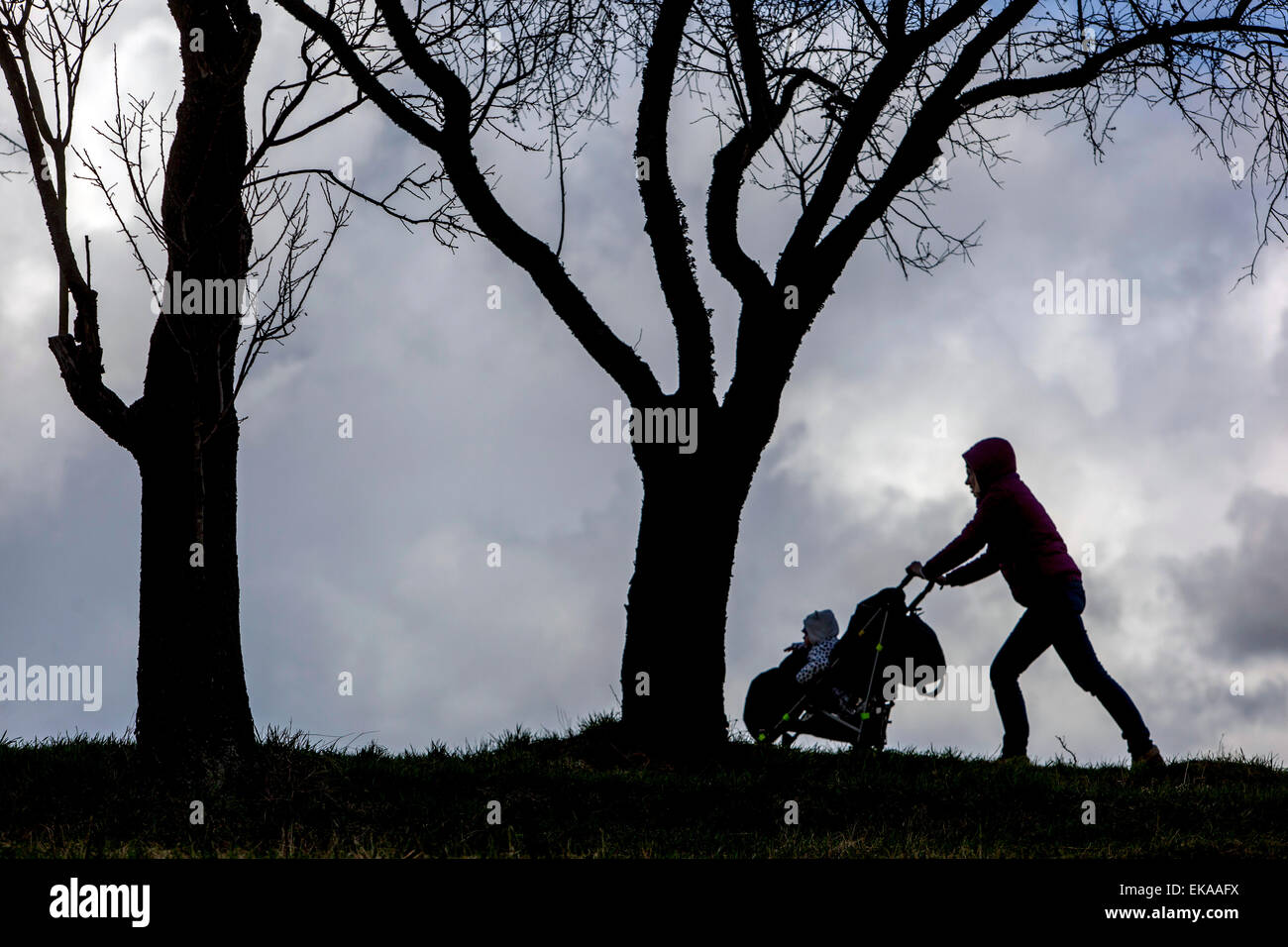 Silhouette einer wandelnden Frau, die einen Kinderwagen schiebt Stockfoto