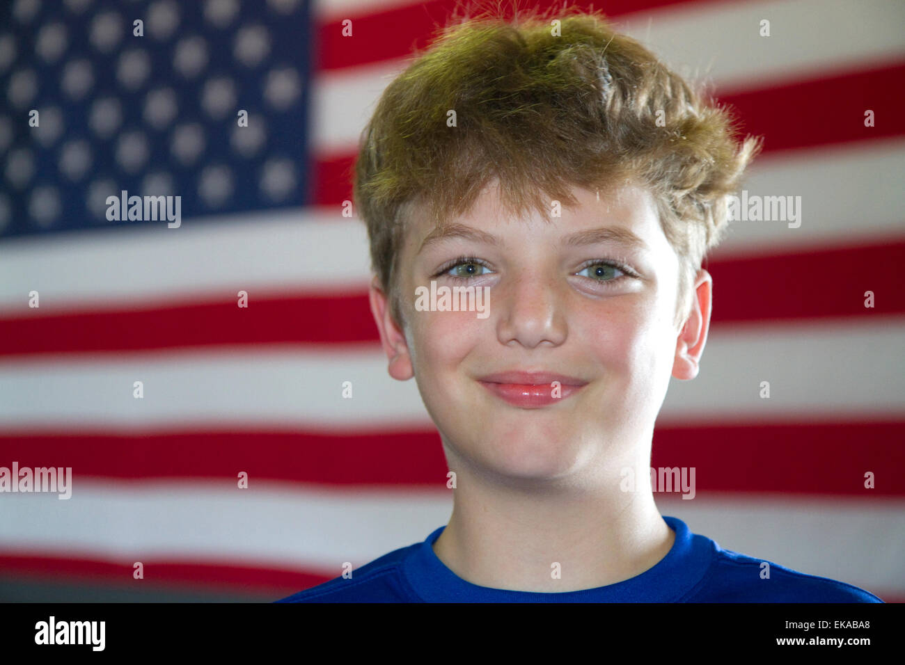 Zehn Jahre alte amerikanische junge steht vor einer amerikanischen Flagge in Charleston, South Carolina, USA. HERR Stockfoto