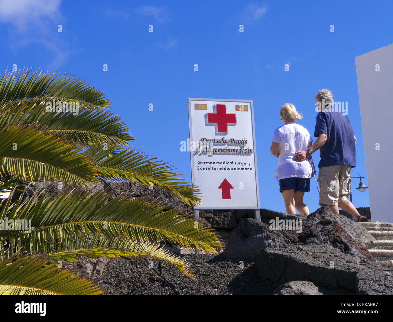 Urlaub healthcare medizinische Behandlung im Ausland Paar und Zeichen für den lokalen medizinischen Behandlung Klinik Pflege in Sun Holiday Lage mit Palmen & blauer Himmel Stockfoto