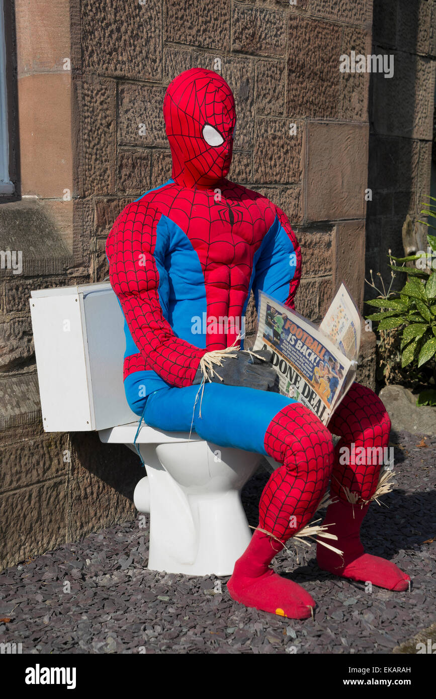 Spiderman Vogelscheuche Scarecrow Festival. Sitzen auf Toilette, die Zeitung lesen. Stockfoto
