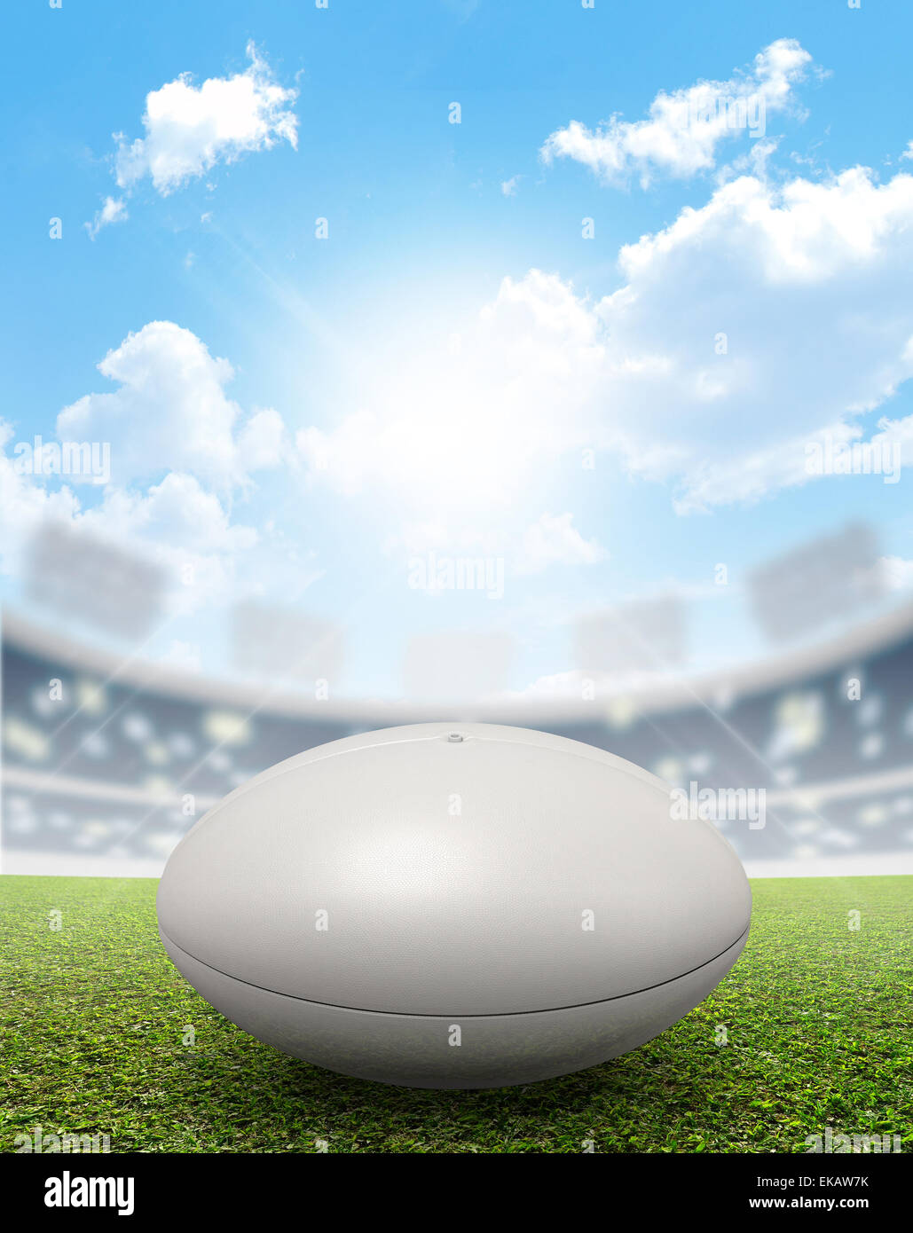 Ein Rugby-Stadion mit einem generischen weißen Rugby-Ball auf einem markierten grünen Rasenplatz tagsüber unter blauem Himmel Stockfoto