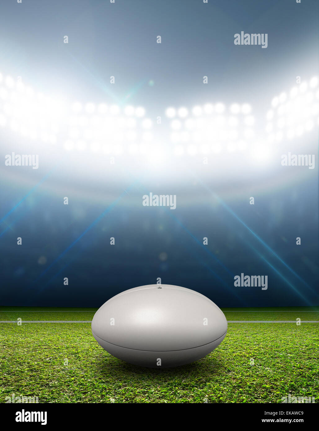 Ein Rugby-Stadion mit einem generischen weißen Rugby-Ball auf einem markierten grünen Rasenplatz in der Nacht unter Flutlicht beleuchtete Stockfoto