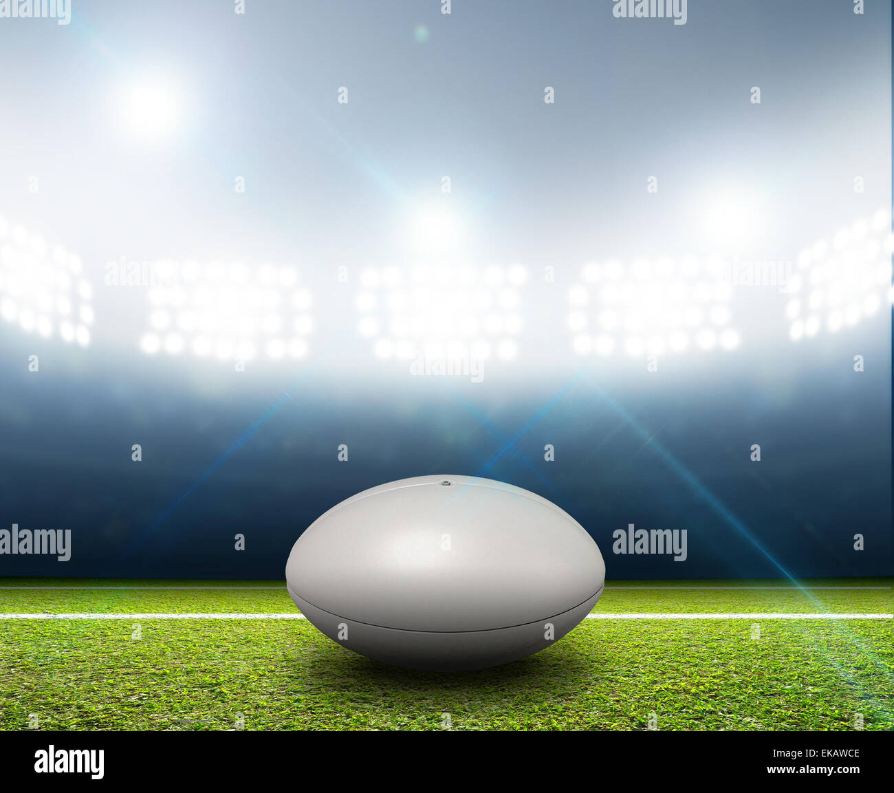 Ein Rugby-Stadion mit einem generischen weißen Rugby-Ball auf einem markierten grünen Rasenplatz in der Nacht unter Flutlicht beleuchtete Stockfoto