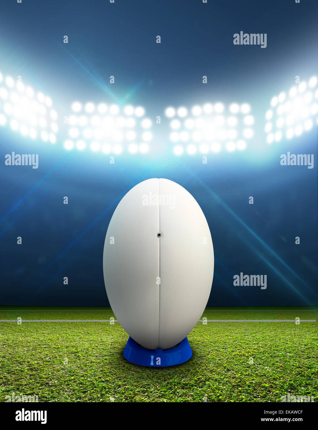 Ein Rugby-Stadion mit einem generischen weißen Rugby-Ball auf einem markierten grünen Rasenplatz in der Nacht unter Flutlicht beleuchtete Stockfoto