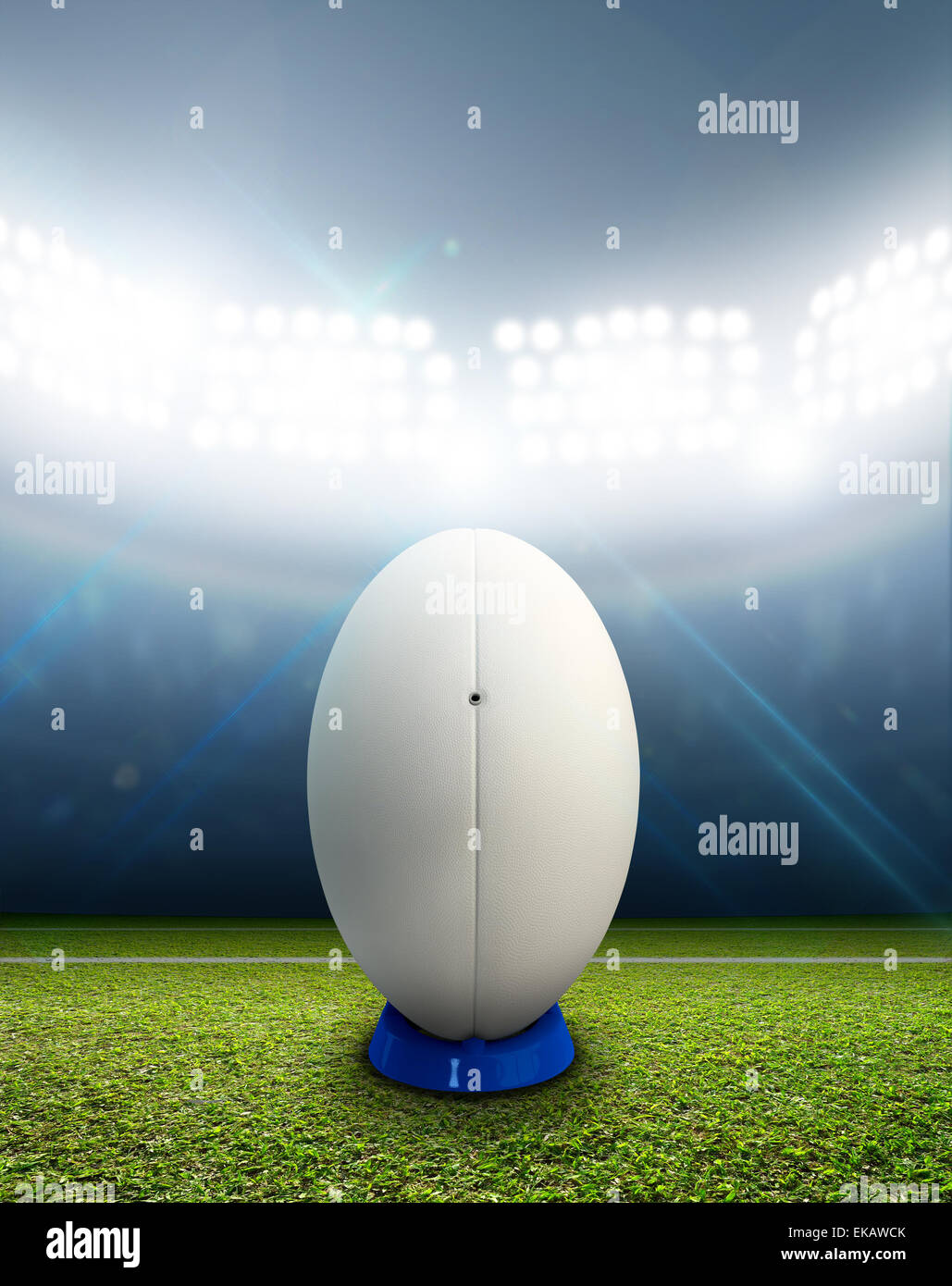 Ein Rugby-Stadion mit einem generischen weißen Rugby-Ball auf einem markierten grünen Rasenplatz in der Nacht unter Flutlicht beleuchtete Stockfoto