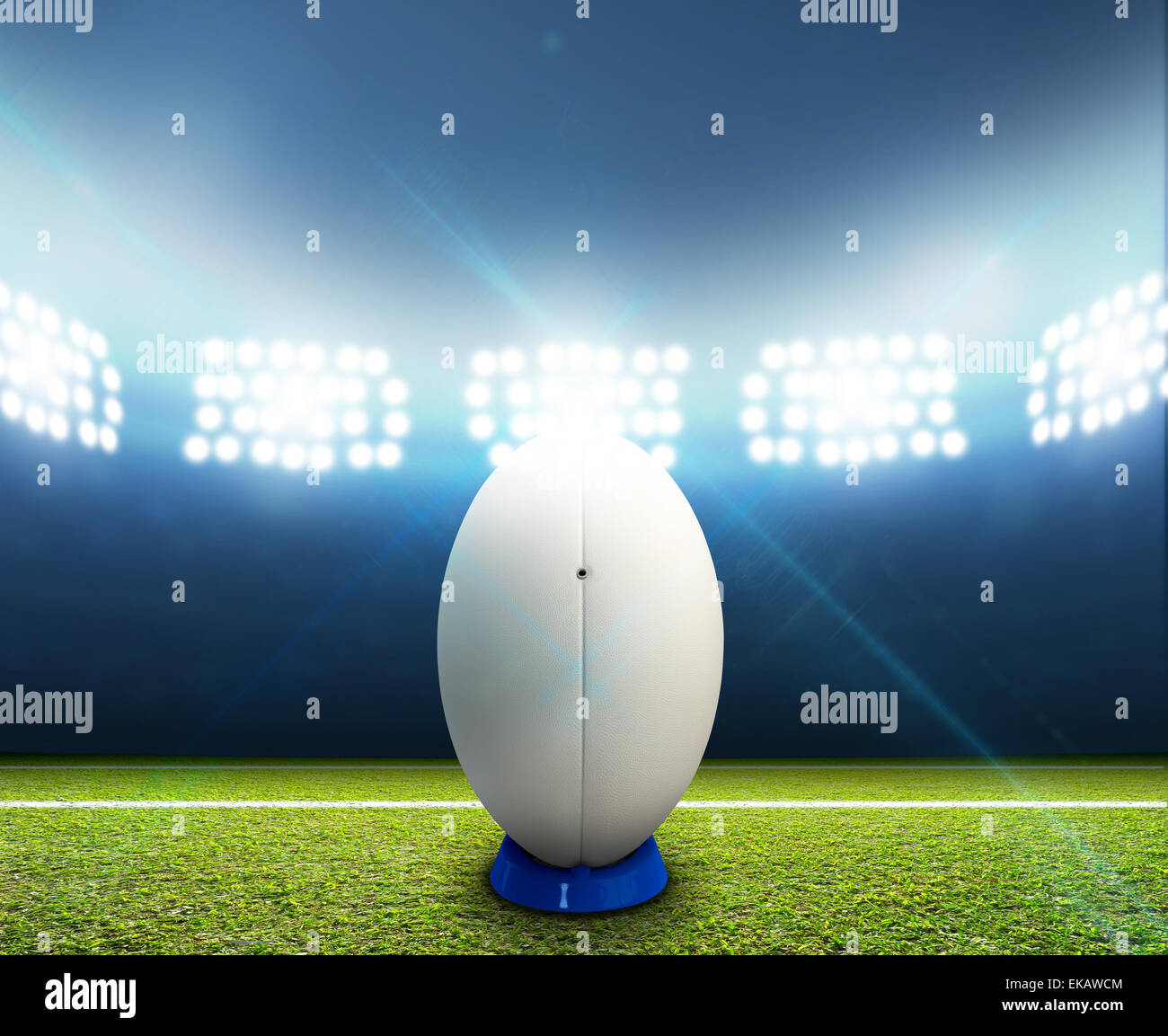 Ein Rugby-Stadion mit einem generischen weißen Rugby-Ball auf einem markierten grünen Rasenplatz in der Nacht unter Flutlicht beleuchtete Stockfoto