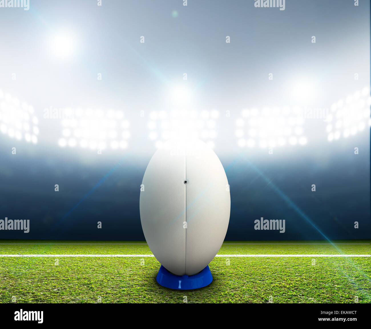 Ein Rugby-Stadion mit einem generischen weißen Rugby-Ball auf einem markierten grünen Rasenplatz in der Nacht unter Flutlicht beleuchtete Stockfoto