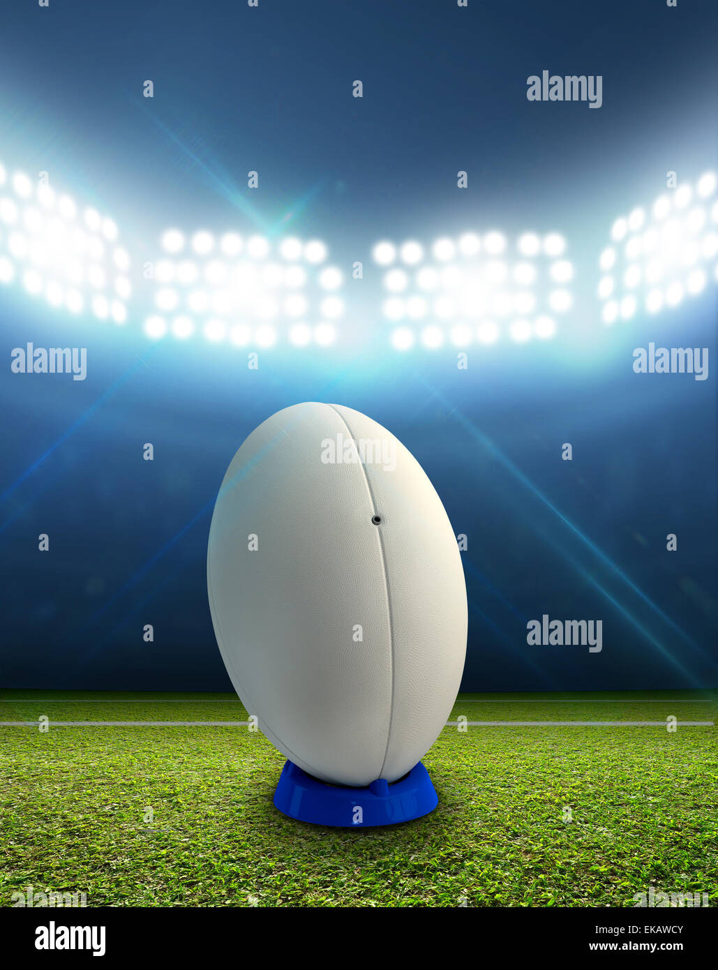 Ein Rugby-Stadion mit einem generischen weißen Rugby-Ball auf einem markierten grünen Rasenplatz in der Nacht unter Flutlicht beleuchtete Stockfoto