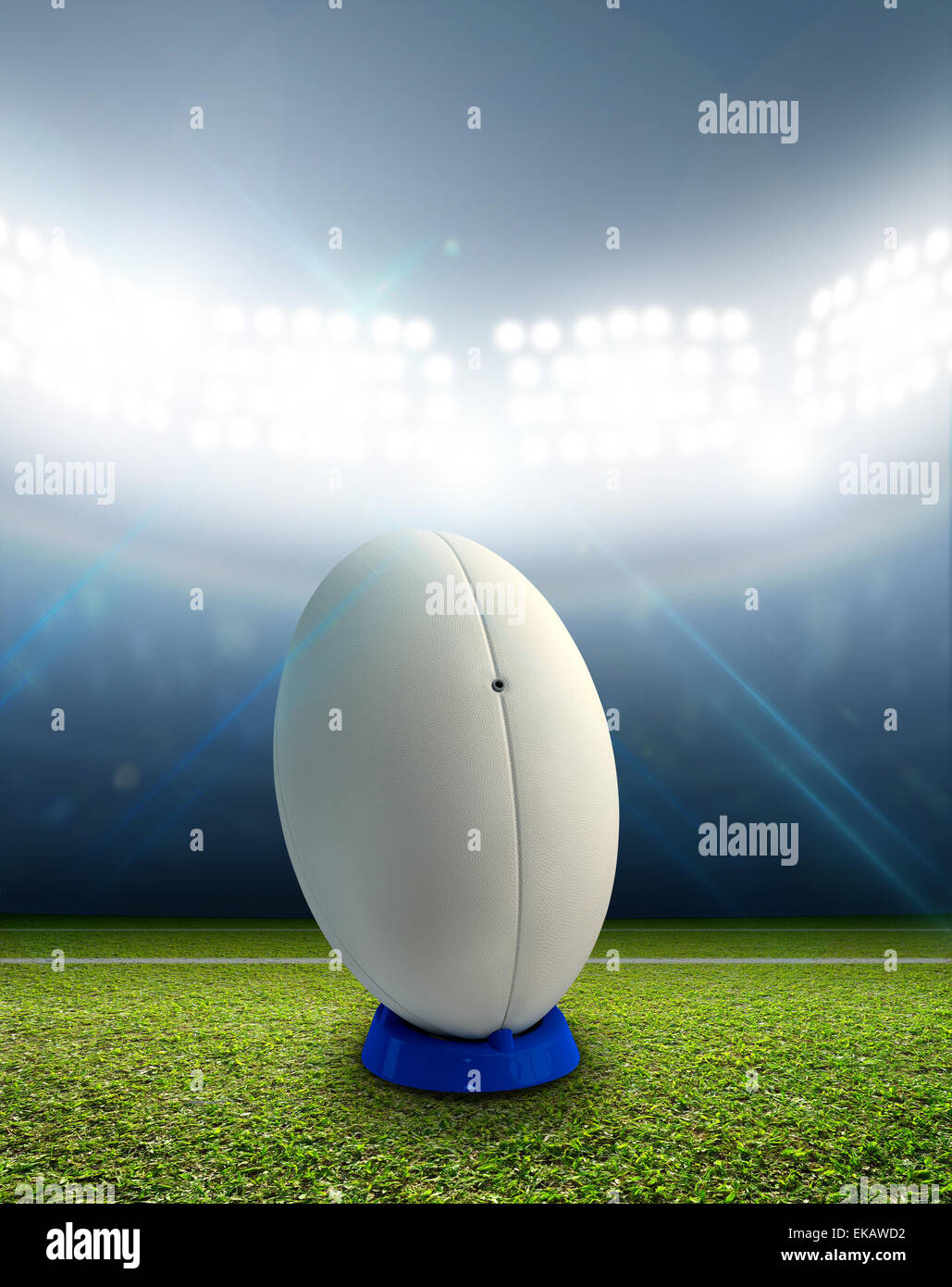 Ein Rugby-Stadion mit einem generischen weißen Rugby-Ball auf einem markierten grünen Rasenplatz in der Nacht unter Flutlicht beleuchtete Stockfoto