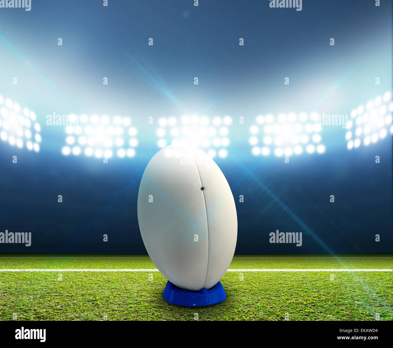 Ein Rugby-Stadion mit einem generischen weißen Rugby-Ball auf einem markierten grünen Rasenplatz in der Nacht unter Flutlicht beleuchtete Stockfoto