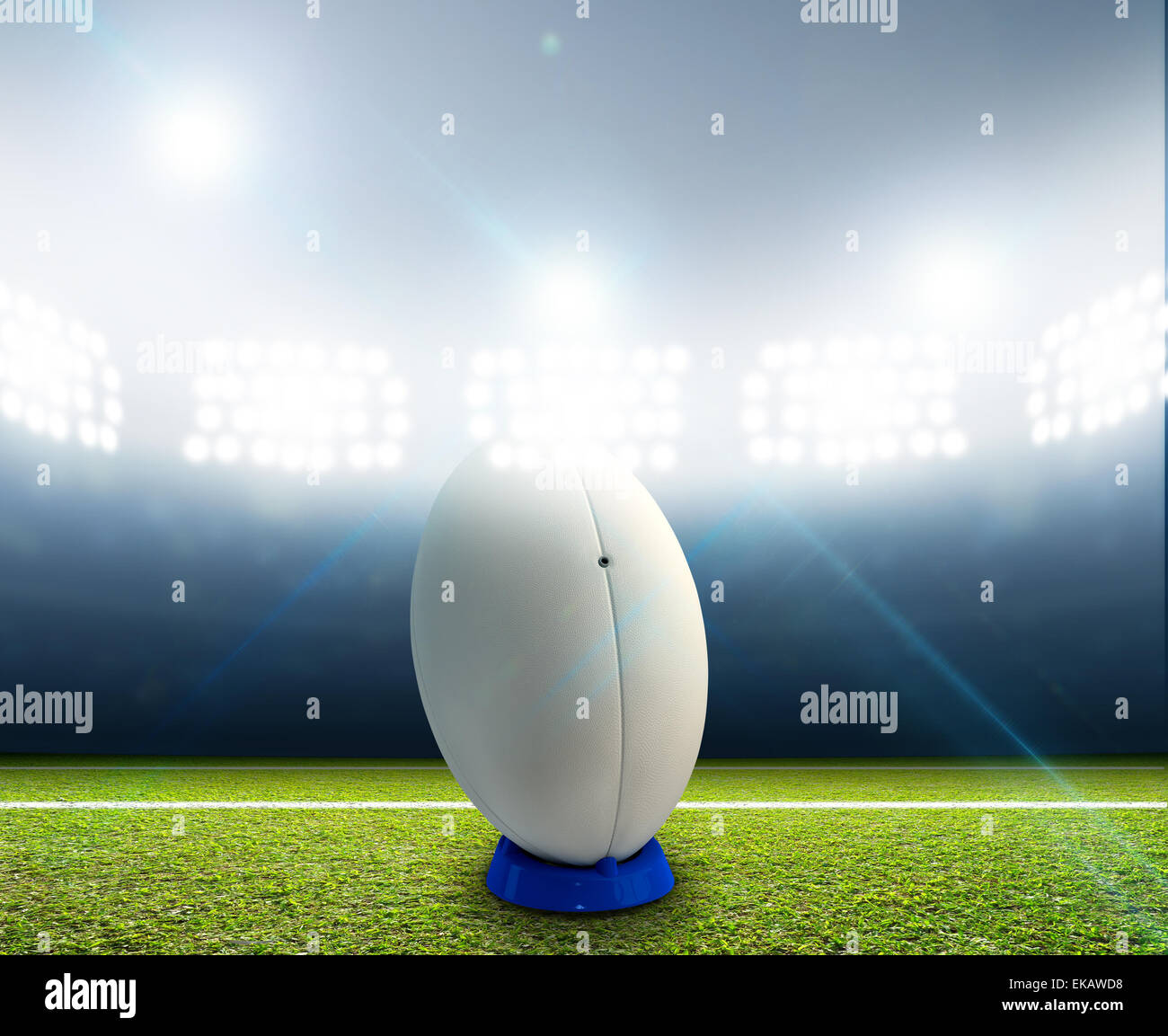 Ein Rugby-Stadion mit einem generischen weißen Rugby-Ball auf einem markierten grünen Rasenplatz in der Nacht unter Flutlicht beleuchtete Stockfoto