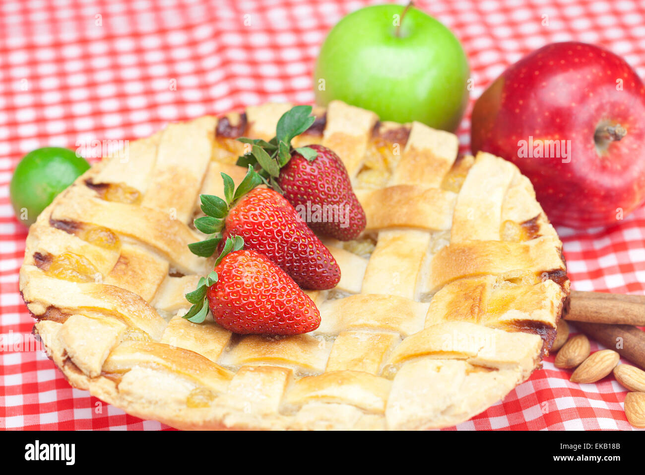 Apfelkuchen, Apfel, Limette, Zimt und Erdbeeren auf kariertem Stoff Stockfoto