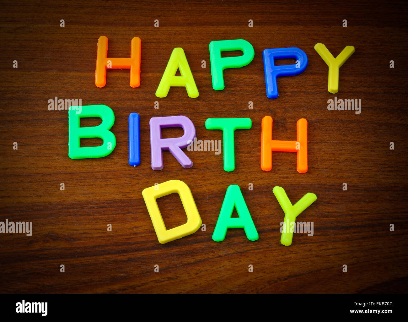 Happy Birthday im bunten Spielzeug-Buchstaben auf Holz Hintergrund Stockfoto