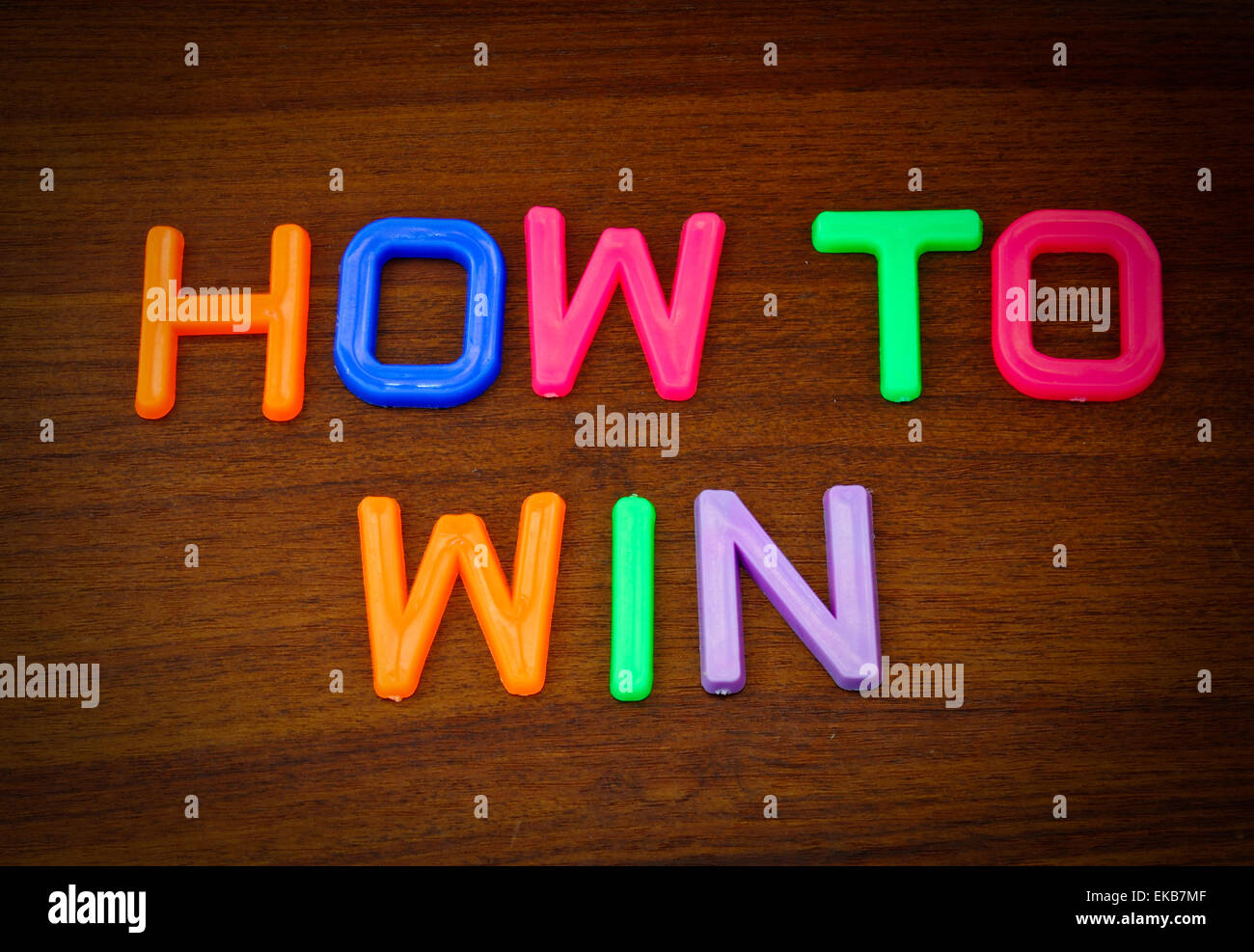 So gewinnen Sie in bunten Spielzeug-Buchstaben auf Holz Hintergrund Stockfoto