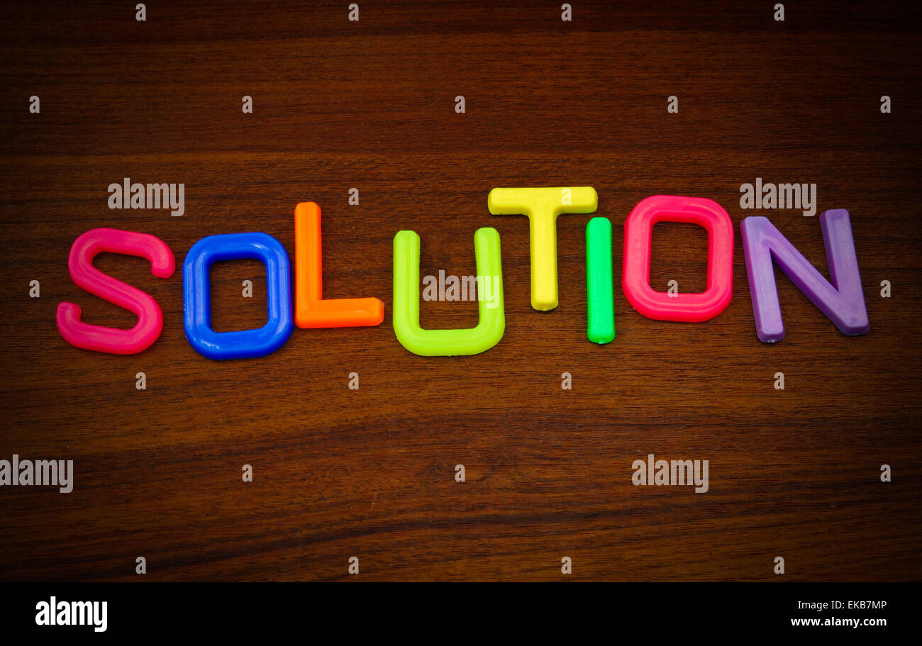 Lösung in bunten Spielzeug-Buchstaben auf Holz Hintergrund Stockfoto
