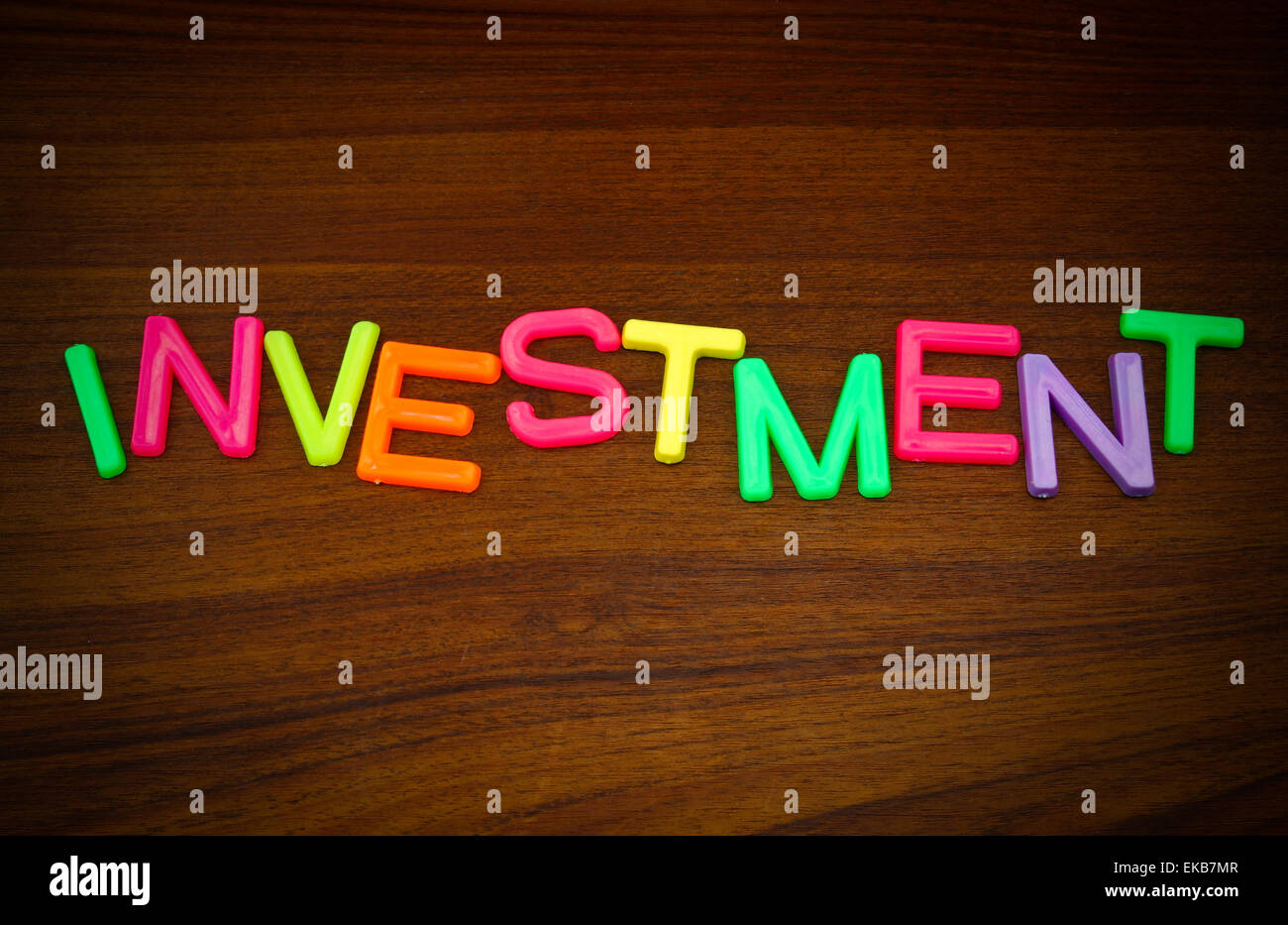 Investitionen in bunten Spielzeug-Buchstaben auf Holz Hintergrund Stockfoto