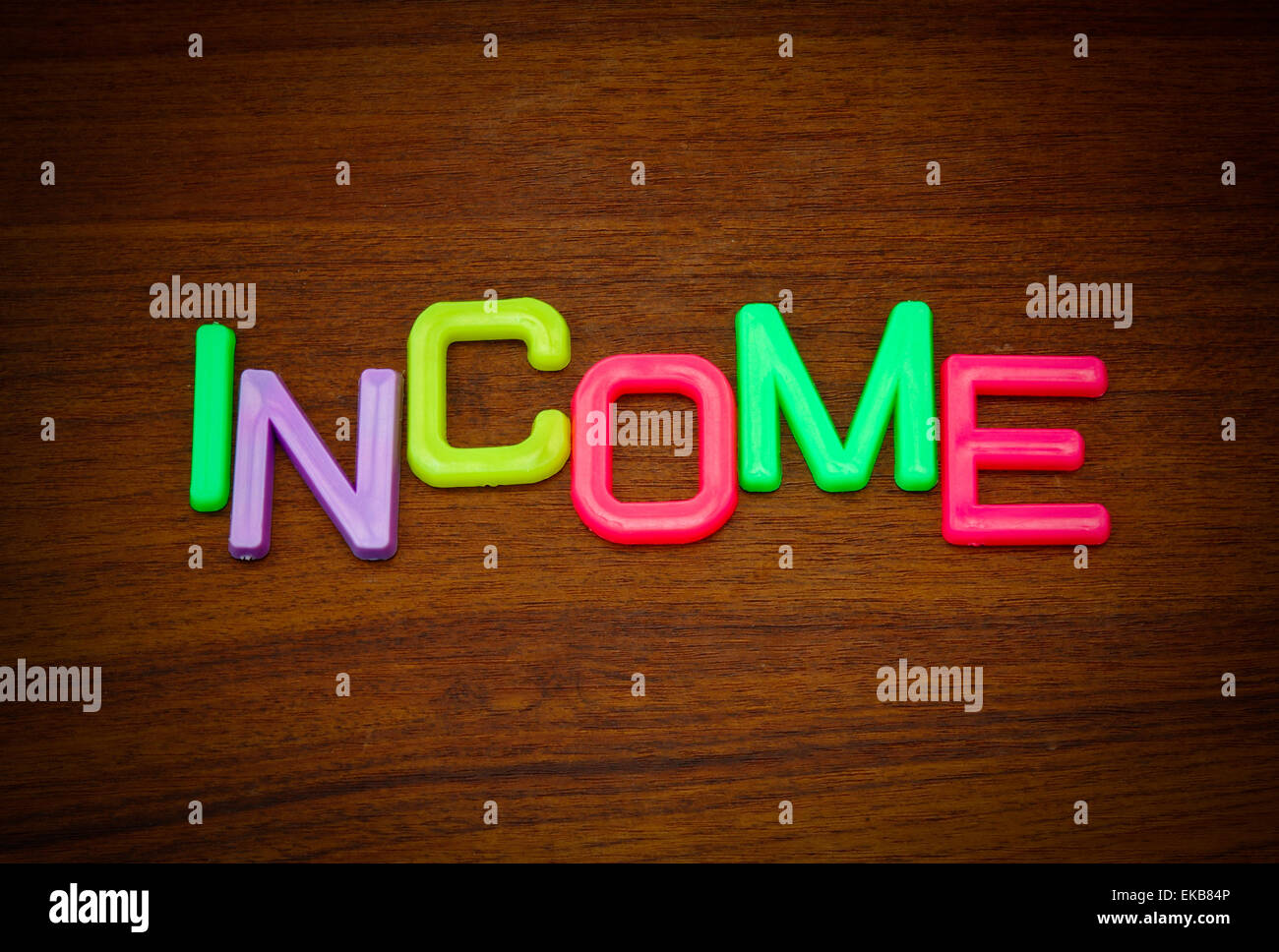 Einkommen in bunten Spielzeug-Buchstaben auf Holz Hintergrund Stockfoto