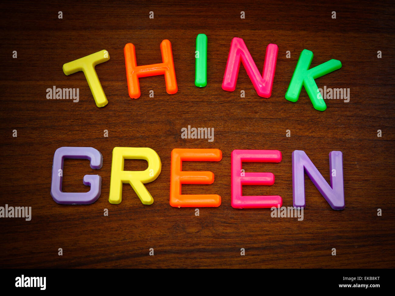 Denken Sie grün in bunten Spielzeug-Buchstaben auf Holz Hintergrund Stockfoto