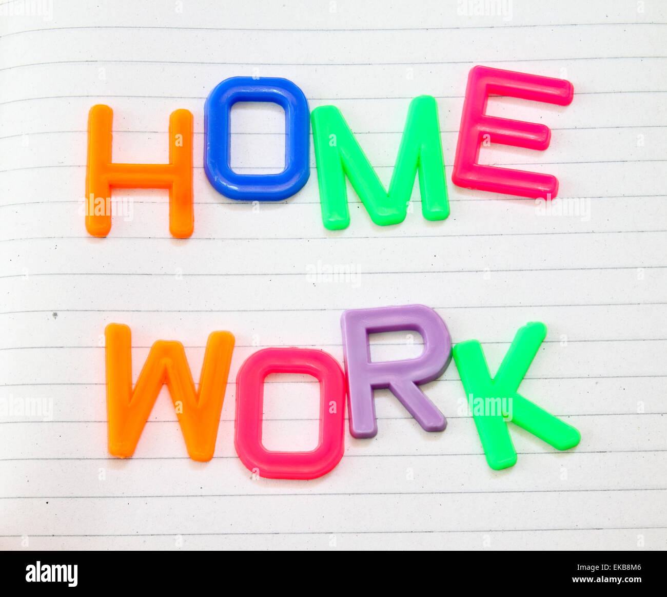 Hausaufgaben in bunten Spielzeug-Buchstaben auf Liniertes Papierhintergrund Stockfoto