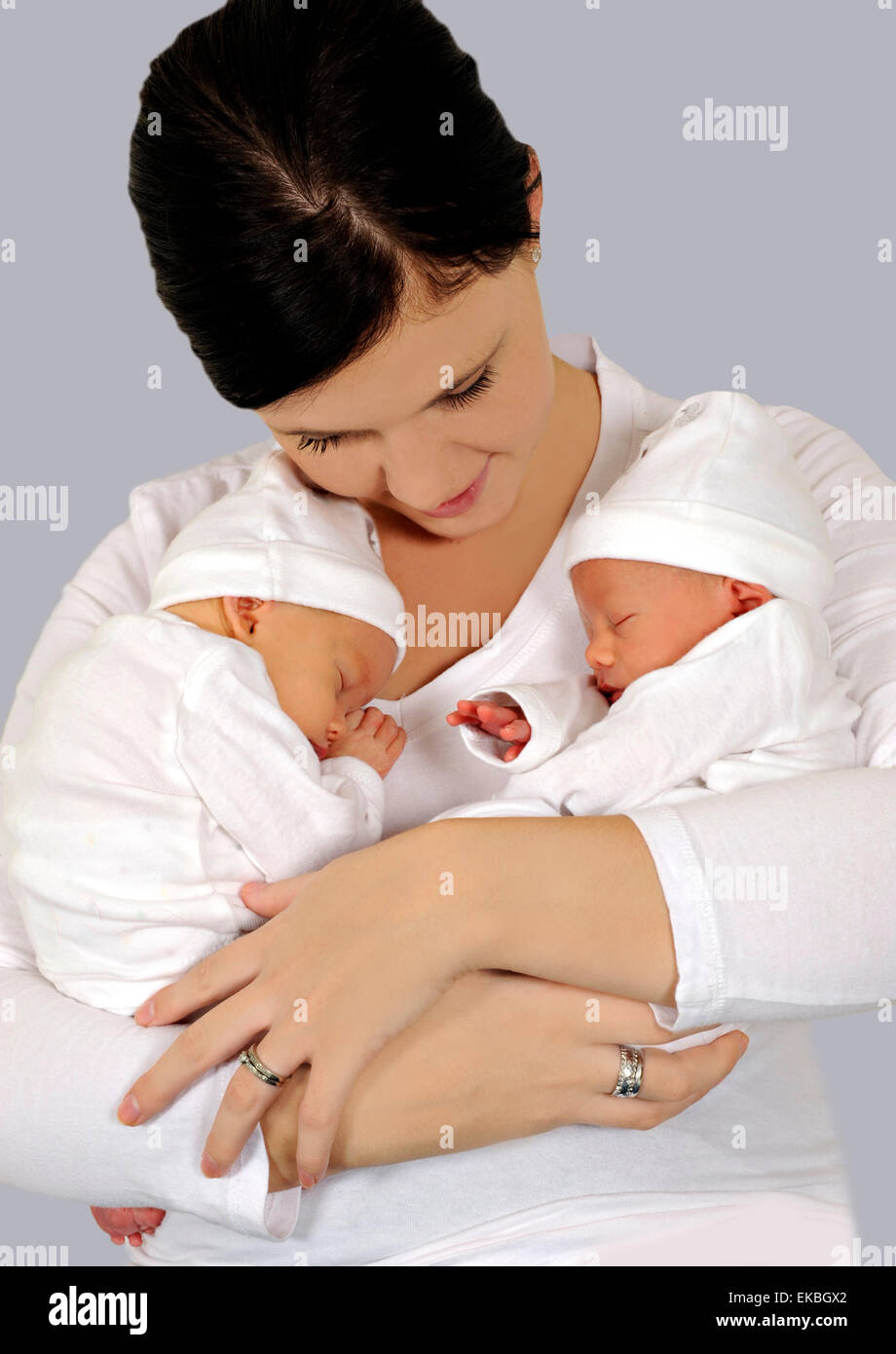 Junge Mutter mit Zwillingen in weißer Kleidung Stockfoto