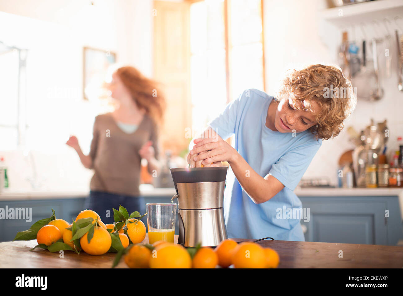 Teenager Entsaften Orange in Küche Stockfoto