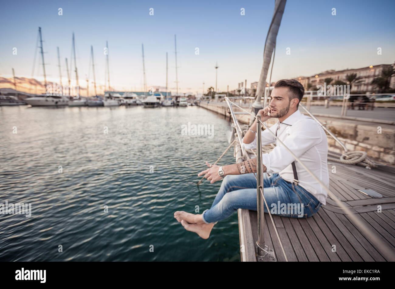 Junger Mann mit Smartphone auf Yacht, Cagliari, Sardinien, Italien Stockfoto