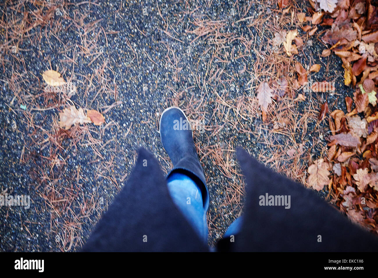Erhöhte Ansicht Frau in Latex Stiefel einen Spaziergang im Herbstlaub Stockfoto