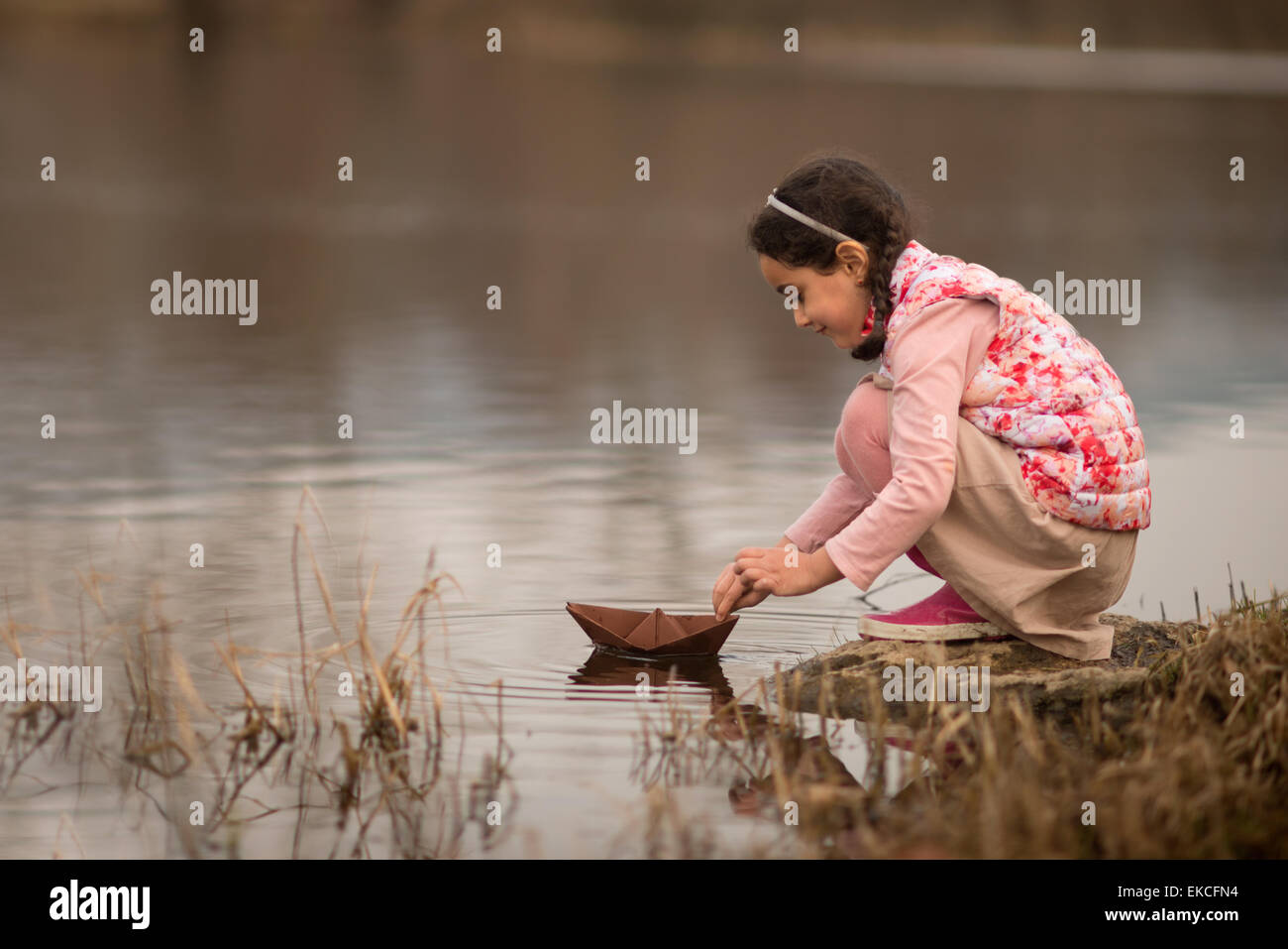 Junge Mädchen spielen mit einem Papierboot Stockfoto