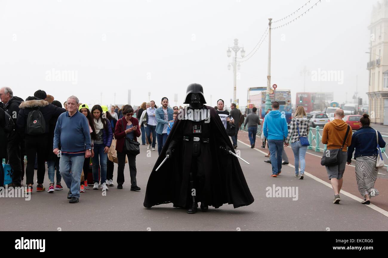 Eine Straße Entertainer gekleidet Anzeige, die Darth Vader entlang Brighton Seafront unter den Massen an einem nebligen Frühlingstag Spaziergänge. Stockfoto